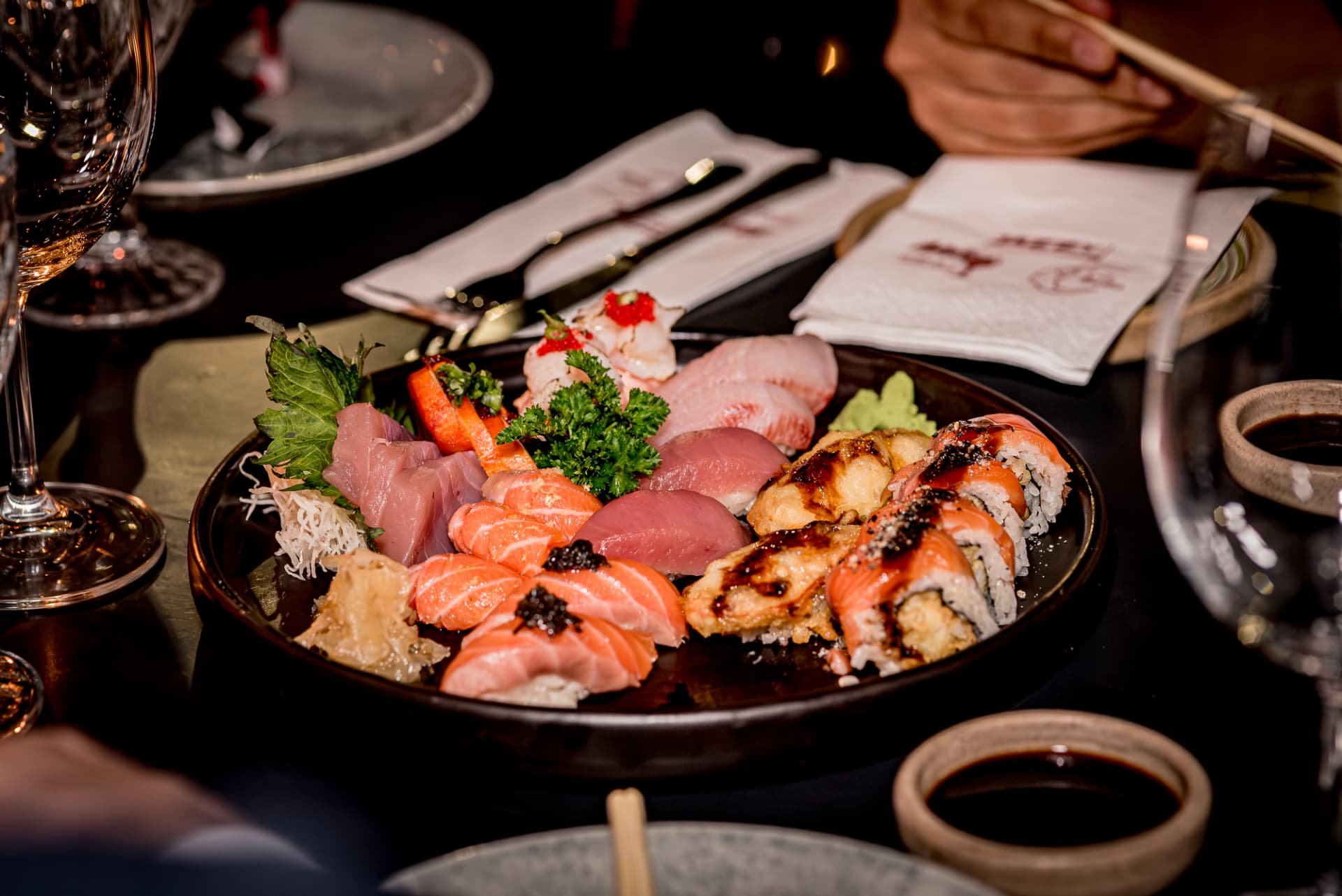 Mesa com combinado de sushis, sashimis, taças e talheres